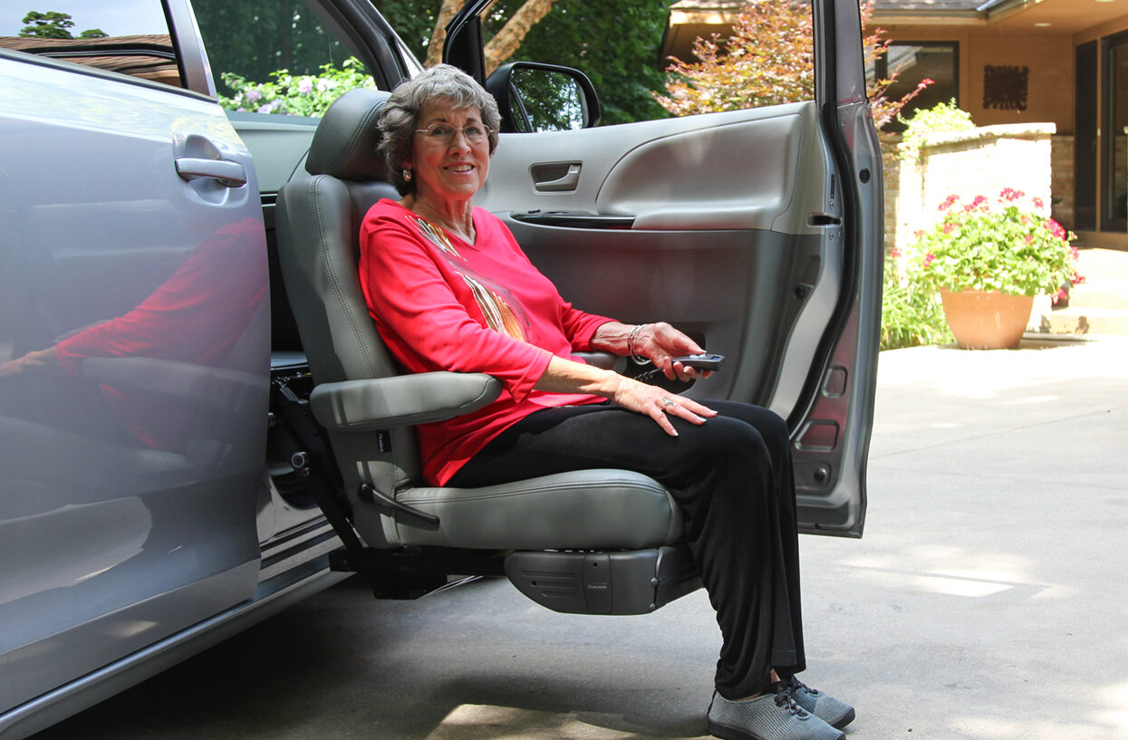 Woman sitting in automotive seat. Seat is lowered outside of the car.